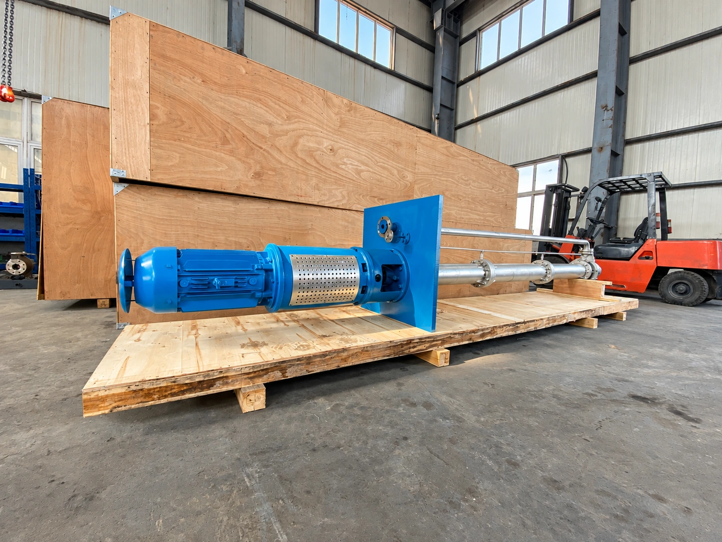 Bơm cột dài màu xanh đặt ngang trên pallet gỗ.